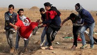 Sekelompok demonstran Palestina mengevakuasi rekannya yang berpakaia Santa Claus karena terluka dalam aksi protes di perbatasan Israel kawasan timur kota Gaza. REUTERS/Mohammed Salem.