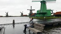 Berlatar belakang kincir angin, sudah bisa ditebak kalau di foto ini Aura Kasih sedang berada di Amsterdam, Belanda. Duh, kok duduknya sendirian aja sih. (Instagram/Aura Kasih)