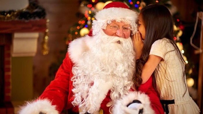 Santa Claus and Little girl,  Christmas Scene. Girl telling wish in Santa Clauss ear in front of Christmas tree