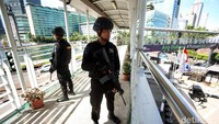 Anggota Brimob siaga di JPO Bunderan HI dengan menentang senjata laras panjang.
