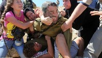 Di foto yang lain, dari 2015, nampak Ahed yang masih 13 tahun mencoba menyelamatkan anak laki-laki dari tangan tentara bertopeng. Anak laki-laki itu ditangkap tentara Israel karena melempari batu.Foto: Ahed Tamimi pada 2015 (AFP/Getty Images)