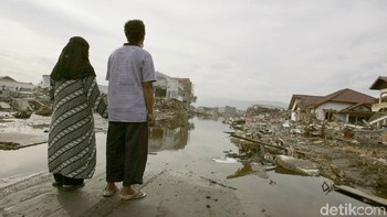 Korban selamat tsunami Aceh, Jasmi dan istrinya Sunarti bergandengan tangan menatap bekas rumah mereka yang tersapu tsunami pada 3 Januari 2005. (Foto:Dimas Ardian/Getty Images). 