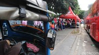 Sebuah bajaj parkir untuk menunggu calon penumpang di saat antrean bus tingkat mengular panjang.
