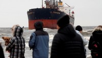 Para pengunjung silih berganti mengabadikan momen pantai dengan latar belakang kapal yang kandas/Foto: REUTERS/Ints Kalnins
