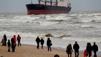 Para pengunjung pantai berpose di depan kapal yang kandas/Foto: REUTERS/Ints Kalnins