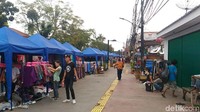 Tenda-tenda para PKL berwarna biru dan merah tertata rapi di sepanjang jalan.