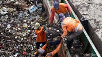 Petugas kebersihan menurunkan sampah dari kapal tongkang.