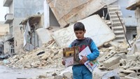 Seorang anak tampak memegang buku dari UNICEF diantara puing-puing bangunan yang hancur di Aleppo. Sejumlah relawan dari UNICEF mendatangi setiap rumah di Aleppo untuk berbicara serta memberikan edukasi resiko sisa-sisa perang kepada setiap anak-anak dan orang tua. Istimewa/UNICEF/Khudr Al-Issa.