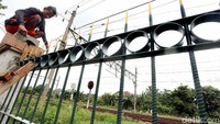 Pekerja saat menyelesaikan pembangunan pagar pembatas.
