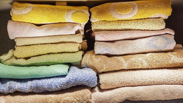 Handuk A lot of clean towels on white shelves in bathroom.