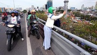 Penumpang ojek online ikut turun dan mengabadikan dengan ponselnya.