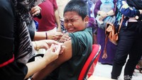 Karena takut bocah ini sampai memejamkan mata saat jarum suntik menyentuh kulitnya.