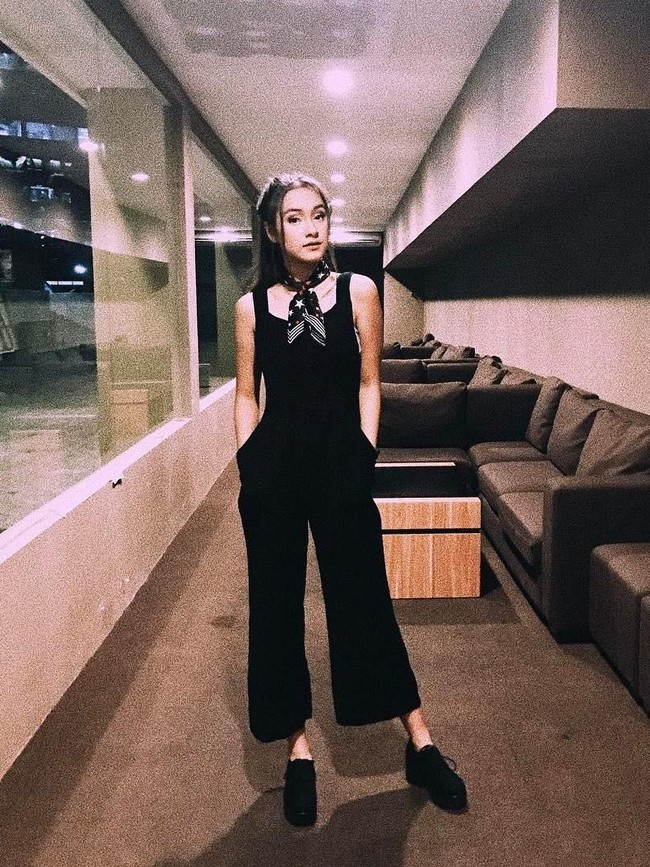Cara lain untuk bergaya dengan jumpsuit adalah pilih tampilan monokrom. Misal, serba hitam head to toe. Dan pilih satu aksesori sebagai statement agar penampilan tidak membosankan. Caitlin memilh bandana dengan motif bernuansa putih yang diikatkan di leher. (Foto: Instagram/Caitlin Halderman)