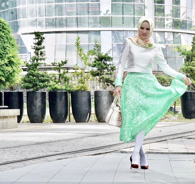 Berpose untuk mempromosikan brand scarf miliknya, Angel Lelga memadukan atasan putih dengan aksen hijau di ujung lengan dan rok hijau serta tak ketinggalan tas Hermes Birkin miliknya. Foto: Dok. Instagram Angel Lelga