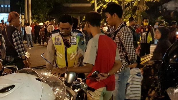 Polisi menilang pengendara motor yang tidak berhelm