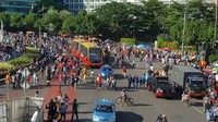 Foto: Zunita Amalia Putri/detikcom. Dengan mobil pengeras suara polisi mengumumkan tidak adanya Car Free Day. Bus Transjakarta pun harus membelah kerumunan warga.