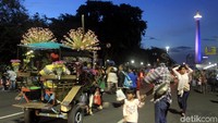 Delman melintas di antara pengunjung Monas yang akan merayakan tahun baru.