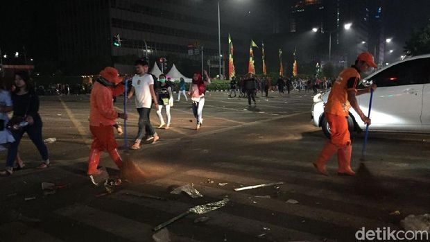 Pasukan Oranye membersihkan sisa sampah tahun baru 2018 di sekitar Monas. 
