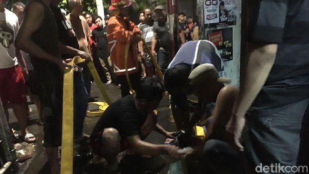 Petugas dan warga berusaha memadamkan api. 