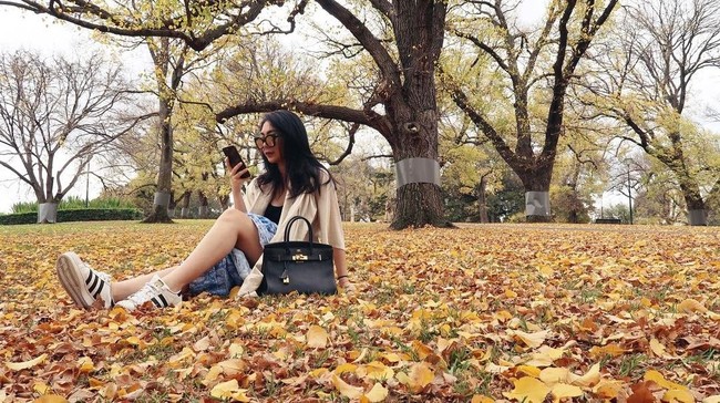 Shania Salsabila bergaya casual dengan sneakers dan rok serta tas Hermes di sebuah taman di Melbourne, Australia. Foto: Instagram