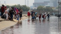 Wisatawan melintas jalan yang terendam banjir rob.