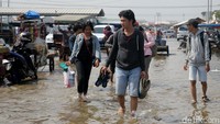 Sejumlah warga terlihat melepas alas kaki mereka saat menembus banjir rob.