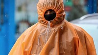 Seorang pria berlindung dari salju dan hujan es dengan mengenakan jas hujan, di utara London, Inggris. (Foto: Dok. Rex Features)