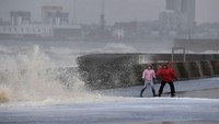 Dua pejalan kaki menghindari terjangan ombak tinggi/Foto: AFP PHOTO / Paul ELLIS