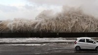 Mobil yang melintas ini melintasi jalan yang berada di pinggir laut/Foto: AFP PHOTO / Paul ELLIS