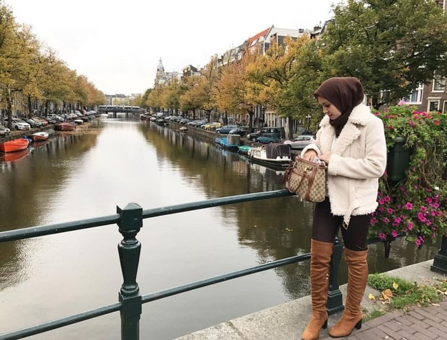 Ratna Galih liburan ke Amsterdam pada 2016 dengan memakai coat berbulu dan boots tinggi. Tas Gucci canvas warna cokelat yang dibawanya kala itu. Harganya belasan juta rupiah. Foto: Dok. Instagram