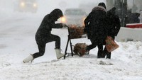Tiga orang warga mendorong troli belanjaan di jalanan yang diselimuti salju tebal di Boston, AS. Brian Snyder/Reuters.