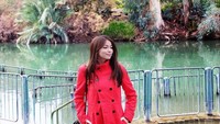 Dengan mantel berwarna merah, Sandra Olga tampak cantik berfoto di tepian Sungai Yordania. Di situs ini konon Yesus dibaptis. (Instagram/Sandra Olga)