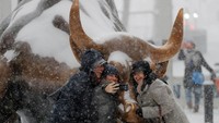 Tiga orang turis asyik mengabadikan momen swafoto di depan patung banteng Charging Bull yang jadi ikon di Manhattan. Ketiga turis ini tetap semringah mesti harus berfoto saat badai salju. (Foto: dok. Reuters)