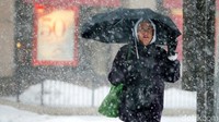 Seorang warga beraktivitas dengan memakai jaket tebal dan payung untuk melawan hawa dingin di Boston, AS. Brian Snyder/Reuters.