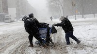 Warga setempat terlihat berjuang melawan terpaan angin dan salju sambil mendorong troli di jalanan Manhattan, New York.  (Foto: dok. Reuters)