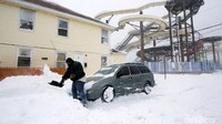 Seorang warga membersihkan salju yang menyelimuti mobil di New Jersey, AS. Eduardo Munoz/Reuters.