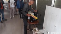 Salah satu aparat kepolisian mengeluarkan barang bukti yang disita dari kamar hotel tempat perekaman video mesum bocah-perempuan dewasa.