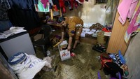 Seorang warga membersihkan rumahnya dari sisa-sisa banjir