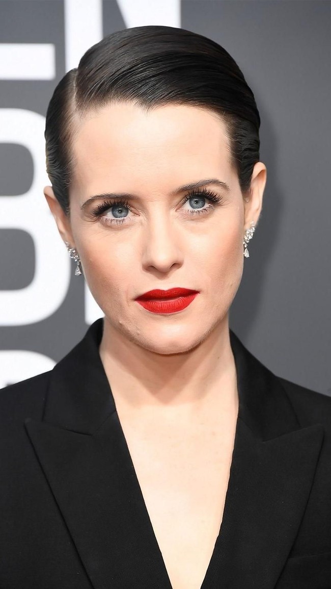 Tampil maskulin dengan setelan jas, Claire Foy menyeimbangkan sisi feminis dengan lipstik merah.  Foto: Getty Images