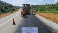 Terlihat beberapa pekerja yang membantu pengaspalan alat berat. Dok. Kementerian PUPR.