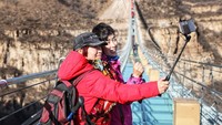 Pengunjung yang tengah mengabadikan momen di atas jembatan dengan foto selfie. Apakah ada traveler yang berani jalan di atas jembatan ini? (Liu Peiran/Xinhua)