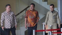Olly yang mengenakan batik dengan dikawal beberapa orang berjalan keluar gedung KPK.