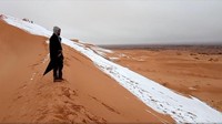 Seorang pria melihat salju di lereng gurun Sahara. Gurun yang biasanya panas itu diselimuti salju. Foto: Reuters