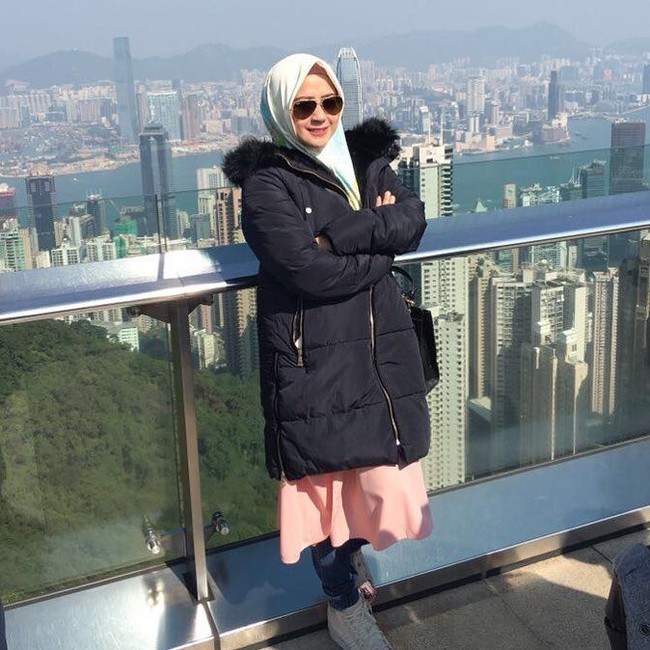 Ini penampilan stylish Shinta Tanjung saat liburan ke Hong Kong. Ia memakai tunik hingga bawah lutut dan celana panjang sebagai tambahan. Agar lekuk tubuh tak terekspos, Shinta Tanjung menambahkan jaket tebal dengan hoodie berbulu sebagai pelengkap dan menghangatkan tubuh. Gaya jilbabnya dibuat simpel dengan pilihan kerudung warna cerah yang cocok dipakai saat pergi di siang hari.  Foto: Dok. Instagram @chintatanjung