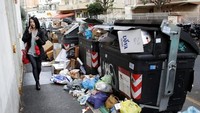 Seorang wanita melewati trotoar yang dipenuhi dengan sampah. 