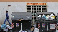 Seorang pria melintasi jalan dekat minimarket. Terlihat sampah yang menggunung di tempat-tempat pembuangan. 