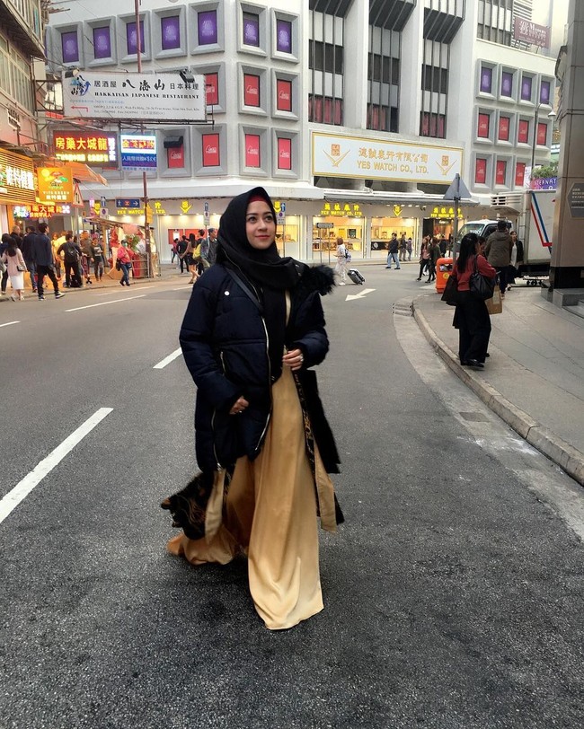 Seperti ini gaya hijab Shinta Tanjung ketika liburan ke Hong Kong dan tetap syari. Gamis panjangnya dipadukan dengan jaket tebal agar tak terlihat mencolok. Ia memakai kerudung hitam supaya tetap netral. Foto: Dok. Instagram @chintatanjung