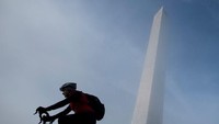 Seorang pesepeda tampak melintas di dekat Monumen Washington yan diselimuti kabut
