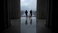 Para pengunjung Lincoln Memorial saat menyaksikan Monumen Washington yang berkabut.