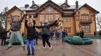 Tiga orang pengunjung berfoto bersama dengan latarbelakang rumah mewah mantan presiden Ukraina. Foto: AFP